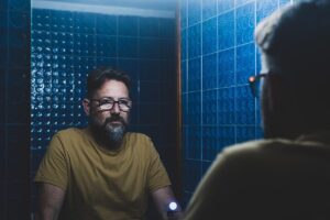 man in blue bathroom looks into trauma and substance abuse