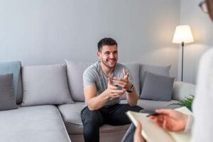 man sitting on couch talks with therapist about oxycodone addiction treatment 
