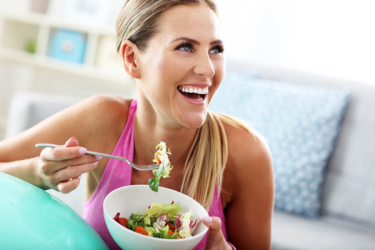 woman laughs with salad while considering the connection between diet and addiction recovery